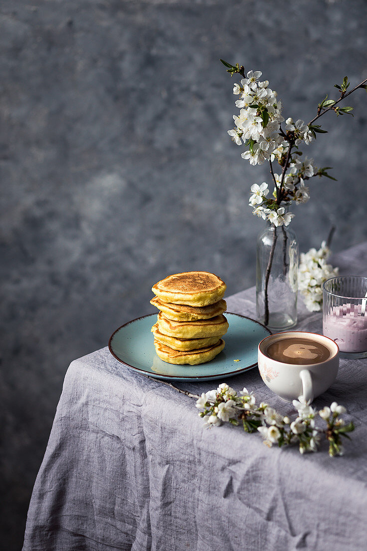 Ein Stapel Pancakes mit Kaffee und Joghurt auf Tisch