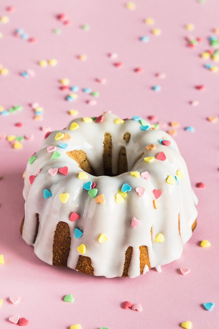 Bundt cake with white glaze and colorful heart shaped sugar sprinkles for Valentine's Day