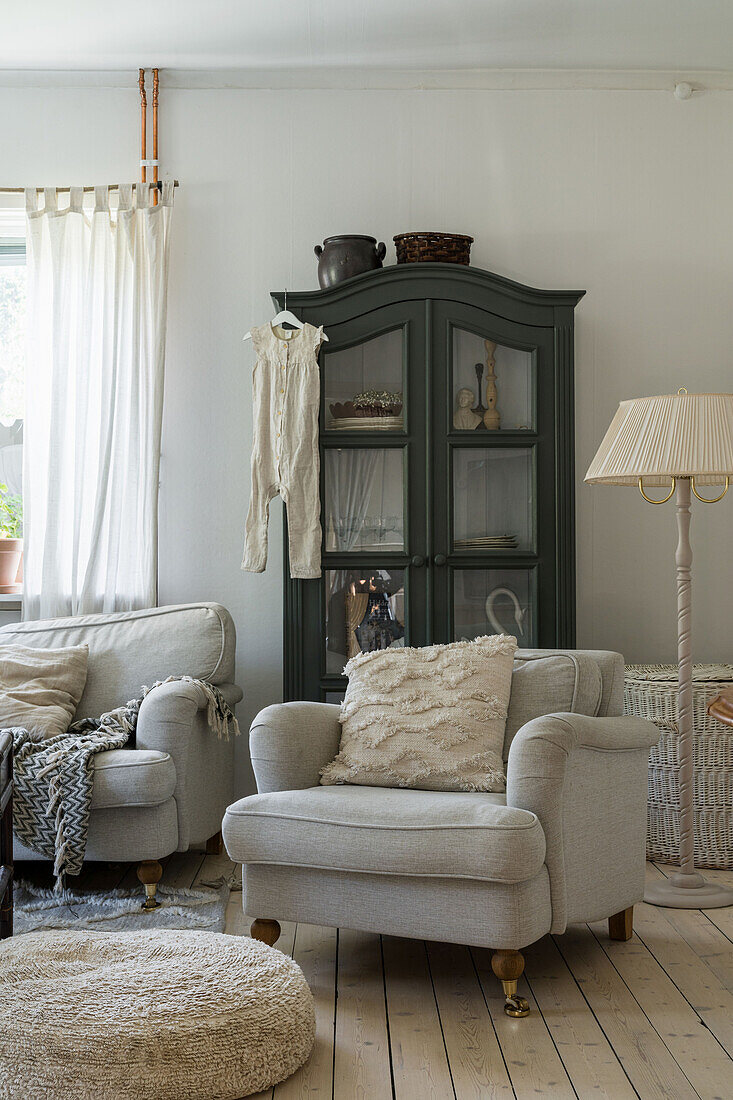 Grey upholstered armchair and glass-fronted cabinet in cosy, rustic living room