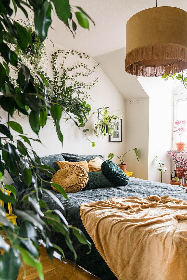 Houseplants and double bed in the bedroom in shades of yellow and green