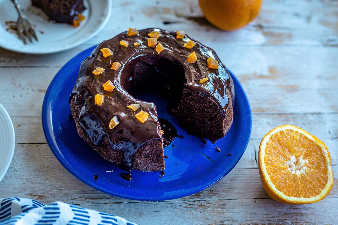 Cutting chocolate bundt cake with coconut sugar and orange chocolate glaze