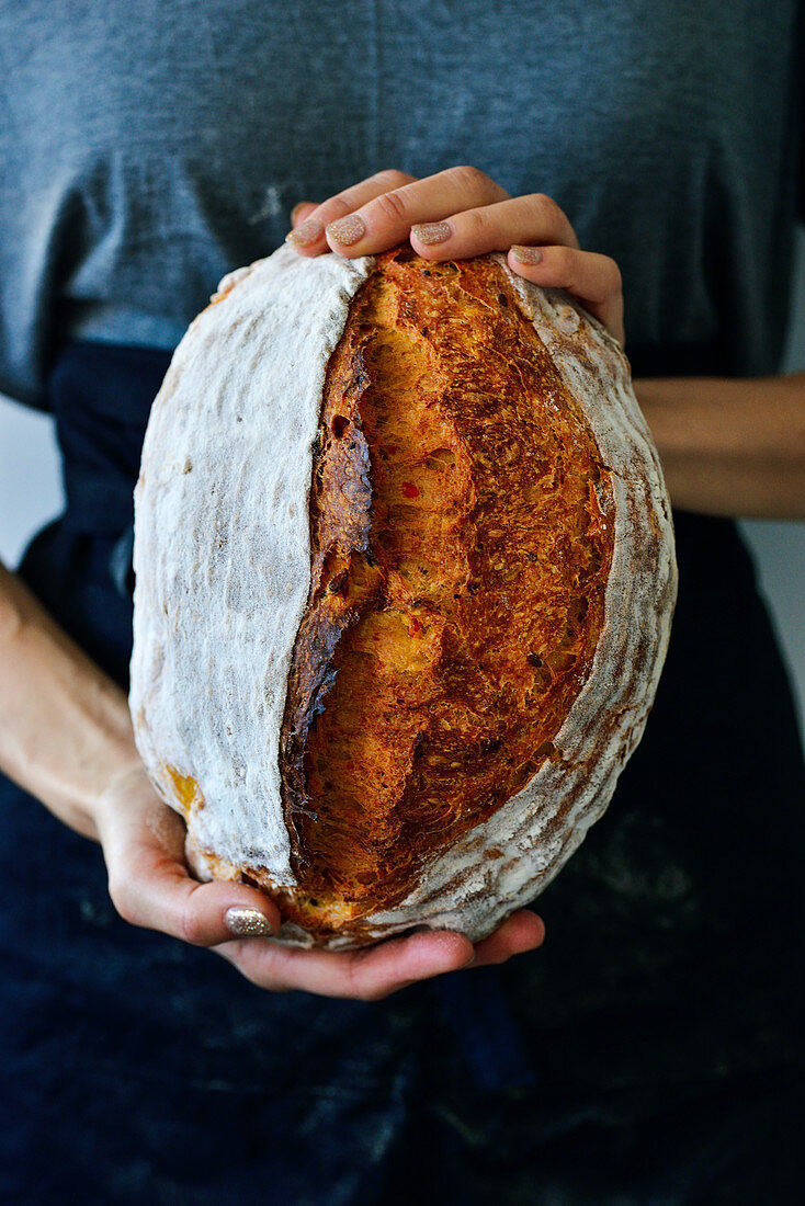 Frau hält Sauerteigbrot in den Händen