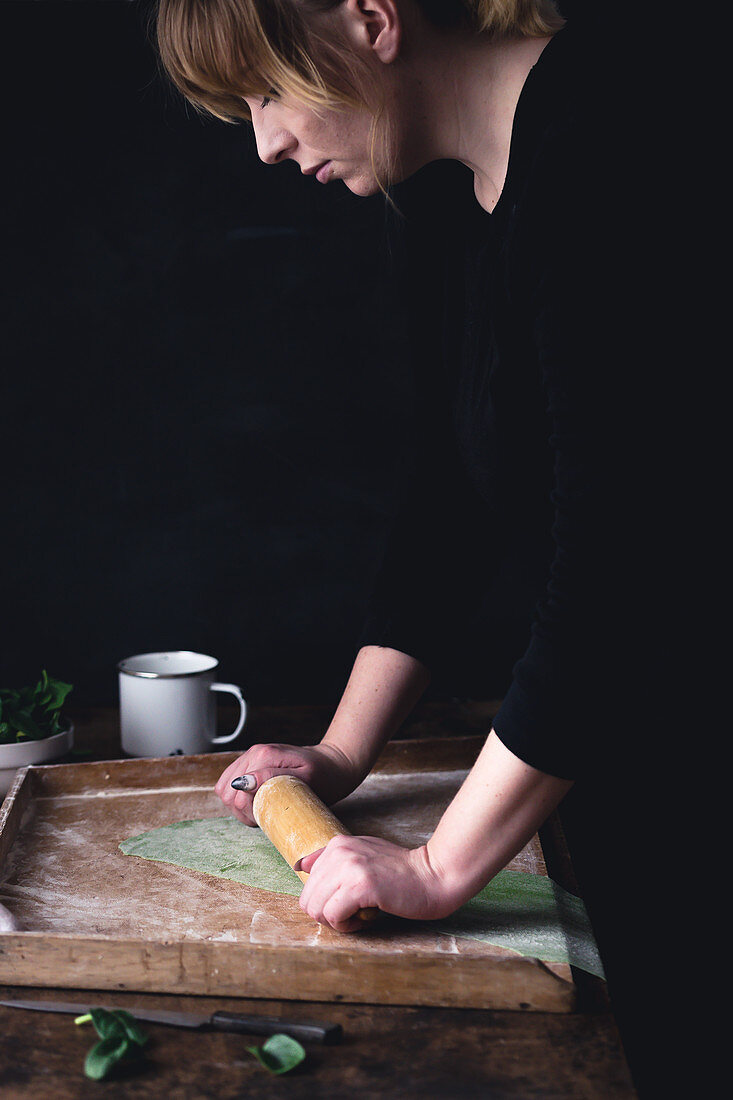 Woman rolling out a green pasta dough