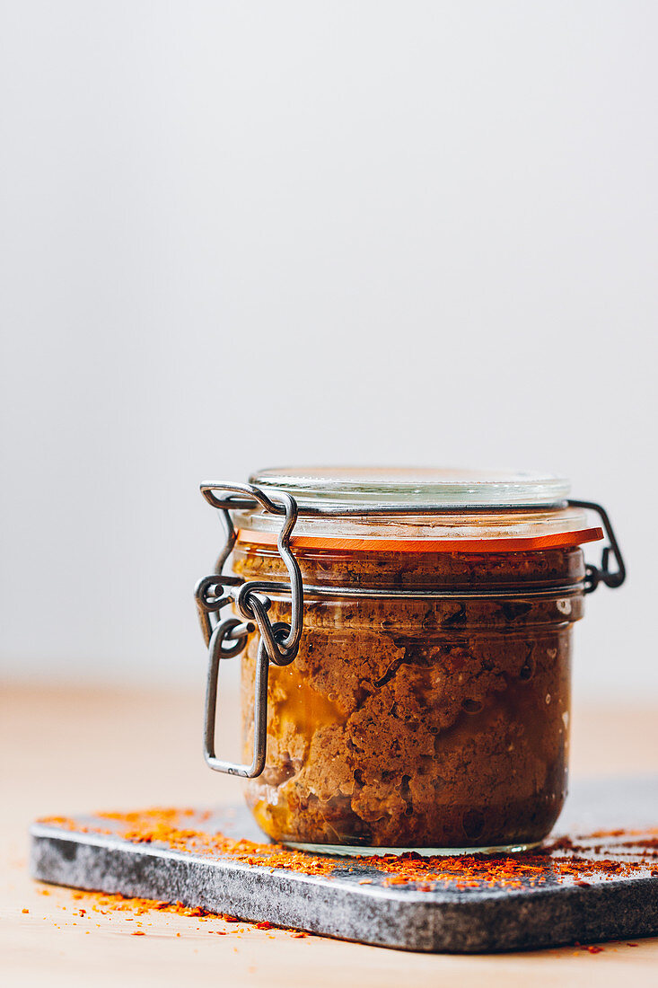 Side view of red pesto inside a glass jar against a neutral background