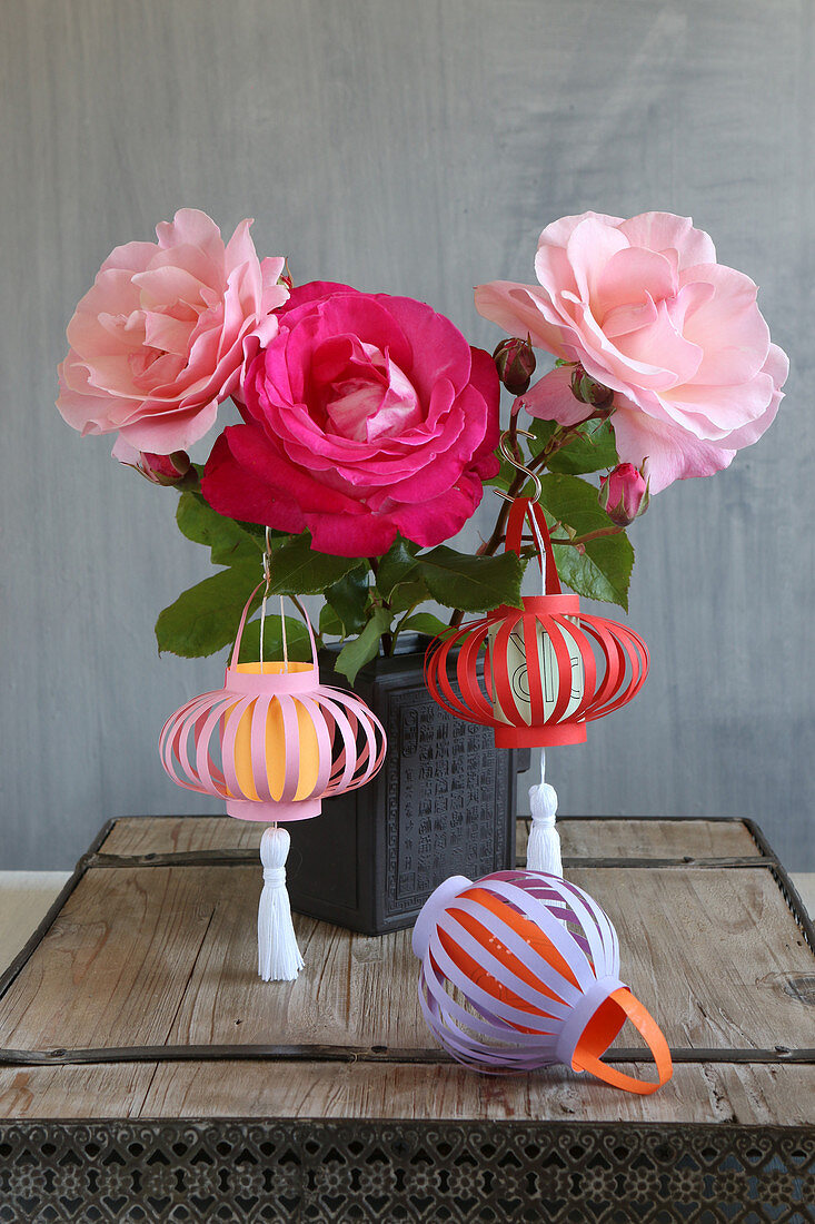 Selbstgemachte Lampions aus buntem Papier am Strauß mit Rosen