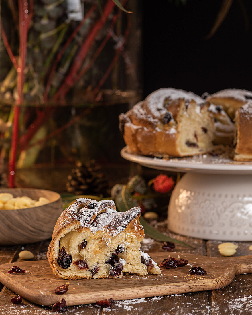 Sweet traditional Kringle with berries and powdered sugar placed on wooden table in kitchen