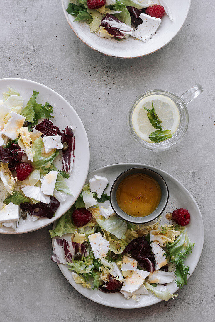 Salat mit Feta und Himbeeren und ein Glas Zitronenwasser