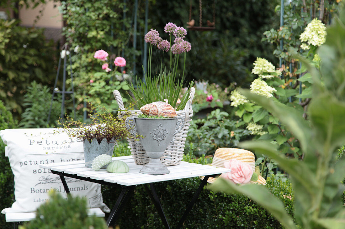 Decorative table with chive blossoms, amphora, zinc case, seashell, and hat