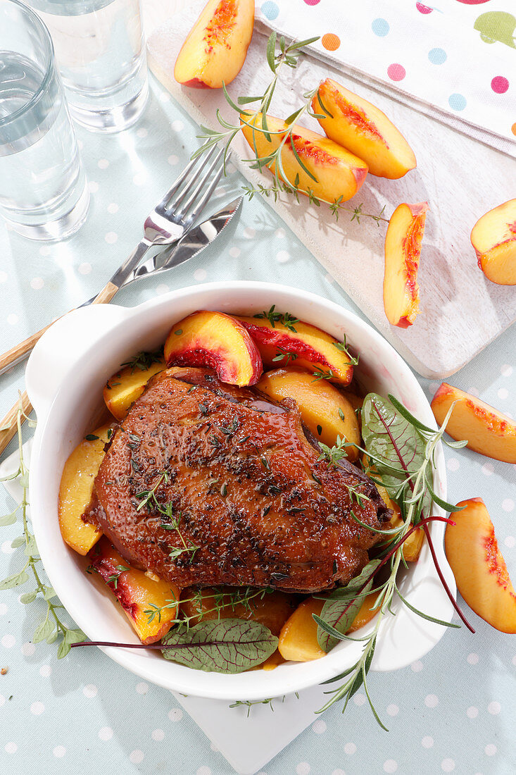 Baked goose breast in a sauce with pieces of peaches