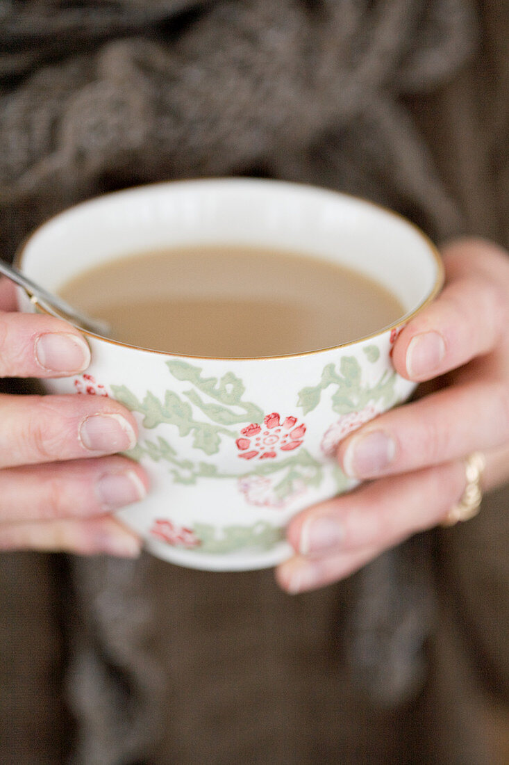 Hände halten Tasse mit Chai-Tee