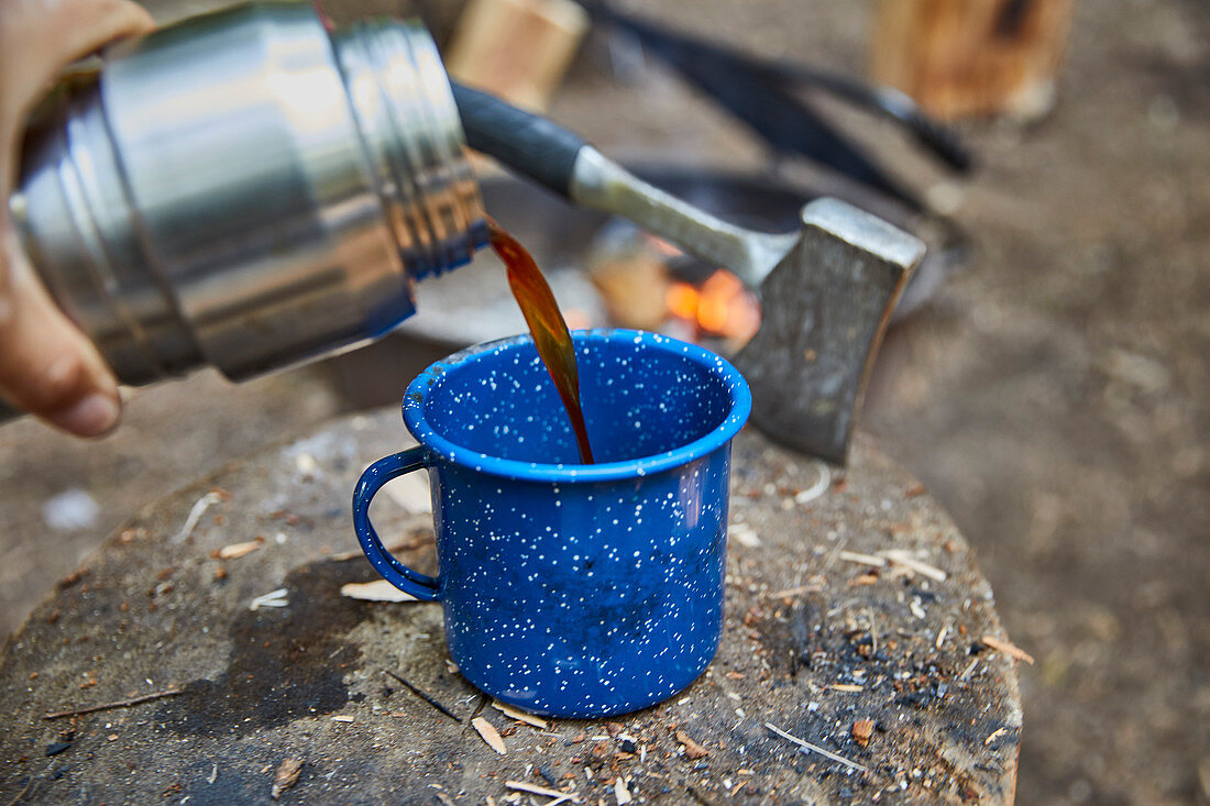 Kaffee auf dem Campingplatz in blauen Becher gießen