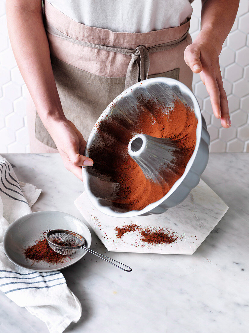 A baking tin being dusted with cocoa powder