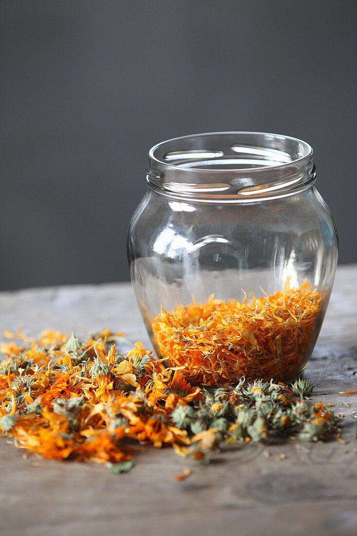 Ringelblumenblüten und abgezupfte Blütenblätter in Glas