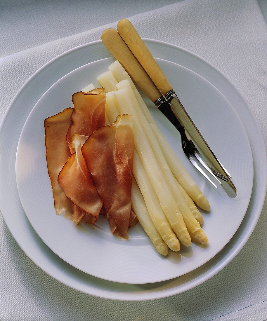 White asparagus with smoked ham on a plate