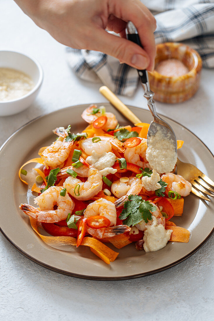 Garnelensalat mit Möhren und Chilischoten mit Dressing beträufeln