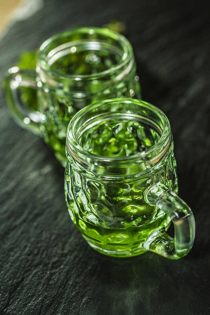 Green absinthe in glasses with handles