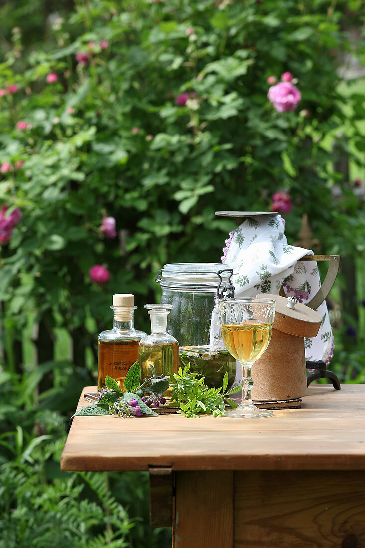 Verschiedene Tinkturen mit Kräutern auf Gartentisch