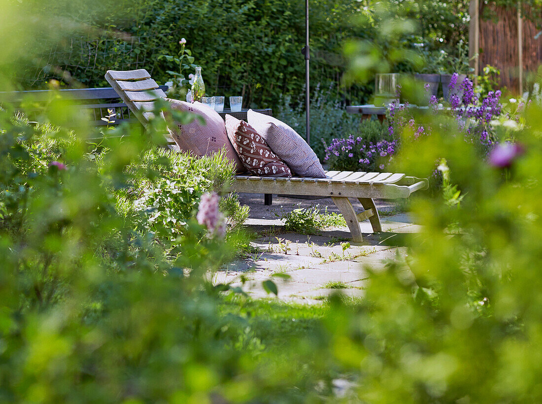 Wooden lounger with cushions on terrace