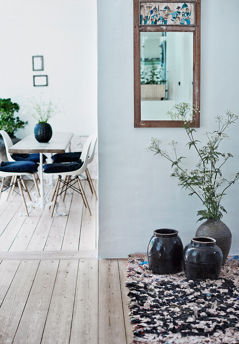 Floor vases on rag rug below vintage mirror