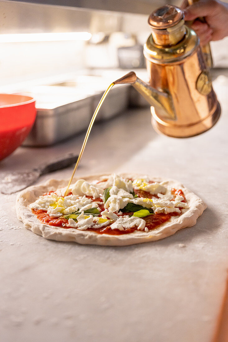 Pizza Margherita zubereiten, mit Olivenöl beträufeln