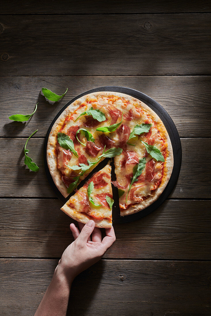 Pizza decorated with fresh basil and arugula leaves