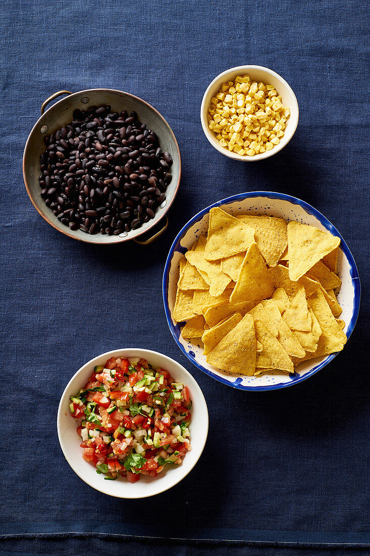 Zutaten für Chilaquiles - schwarze Bohnen, Tortillachips, Mais und Salsa