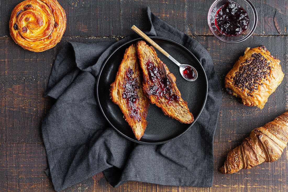 Homemade croissant with cherry jam, bun with chocolate and roll with raisin