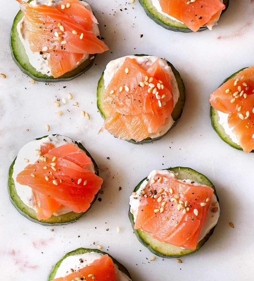 Sliced cucumber topped with salmon, cream cheese and sesame seeds
