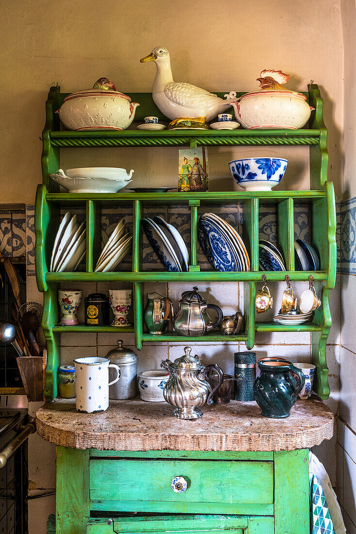 Old green-painted plate rack in rustic kitchen