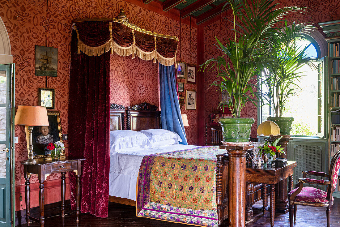 Antique double bed in bedroom with red wallpaper