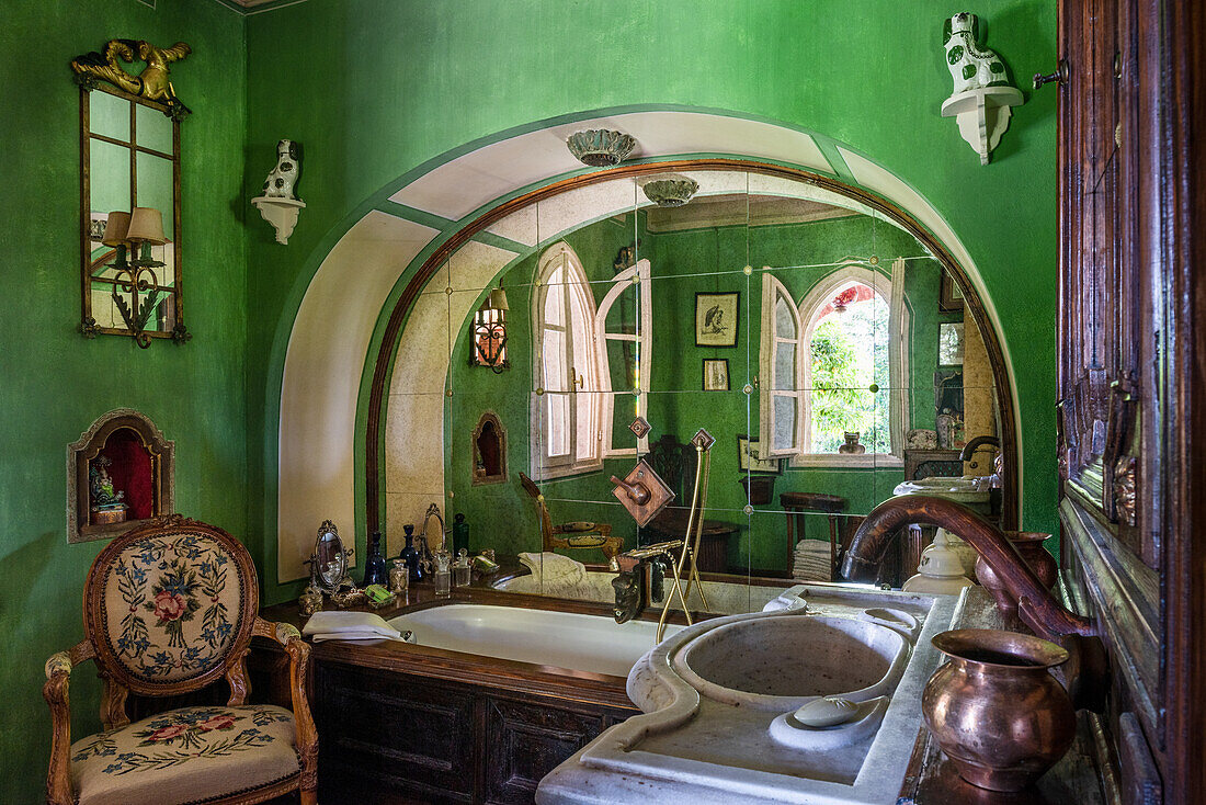 Antique armchair in green-painted bathroom with round arch