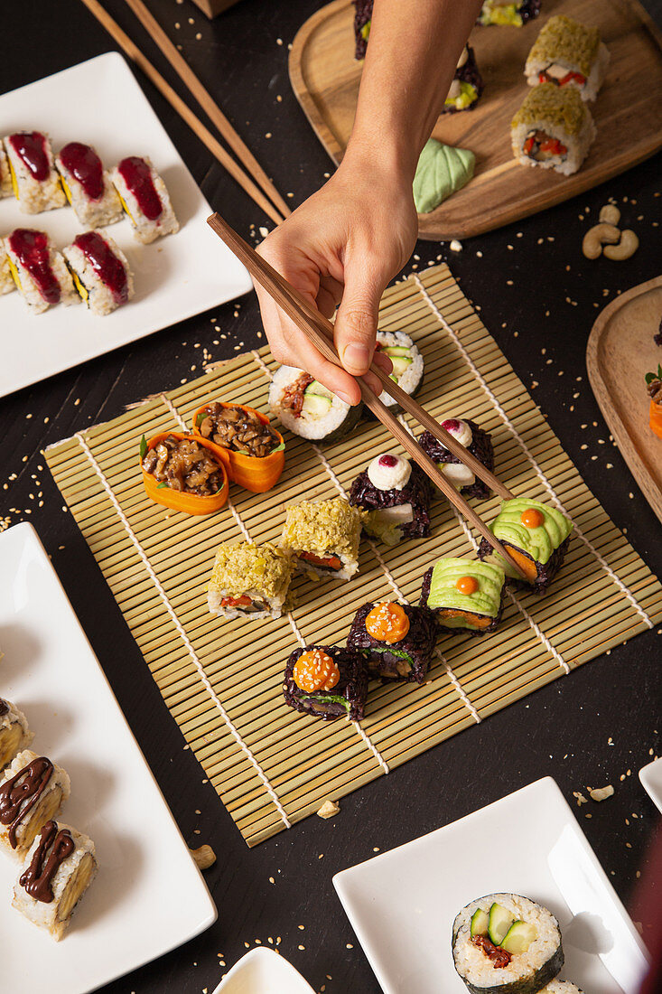 Hand mit Stäbchen nimmt vegetarisches Sushi