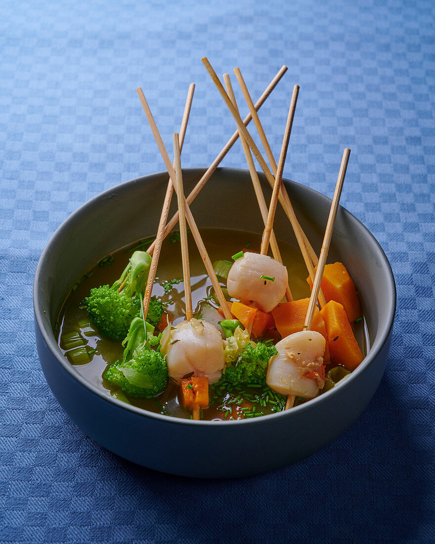 Fondue with scallops and vegetables on wooden skewers