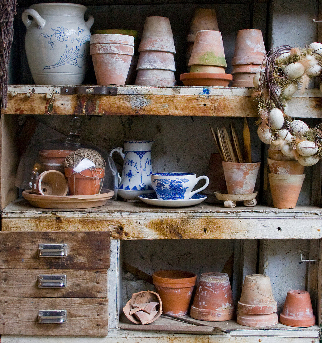 Plant pots, vintage crockery and Easter wreath in old cabinet