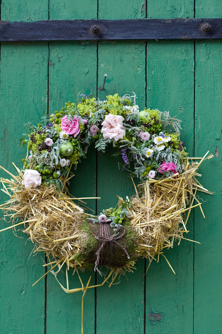 Summer wreath of roses, lady's mantle, chamomile, tufted vetch, green apples and straw