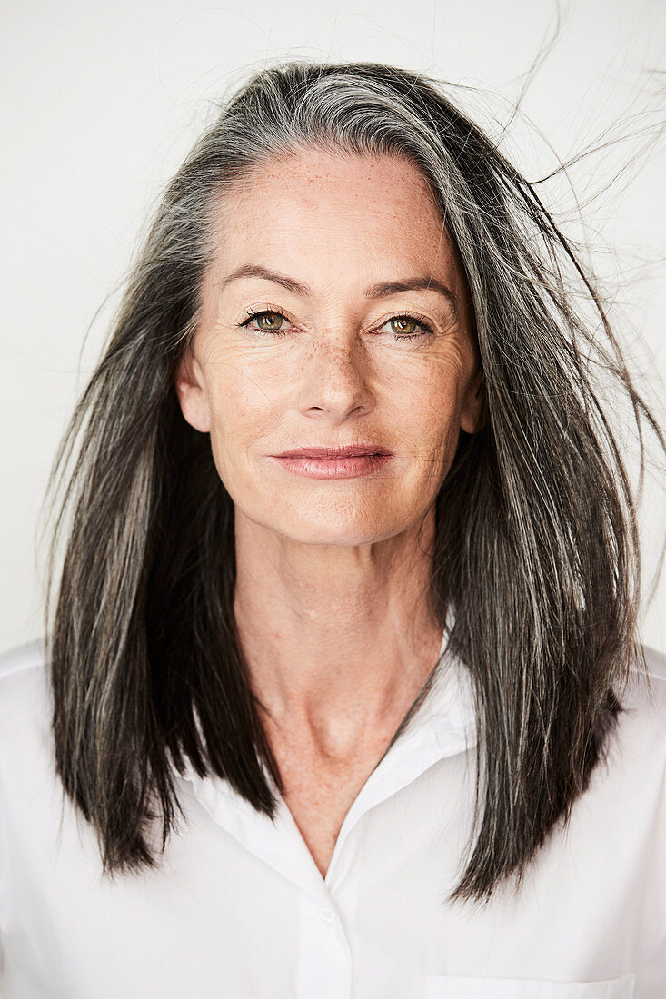 Frau mit grau-melierten Haaren in weißem Hemd