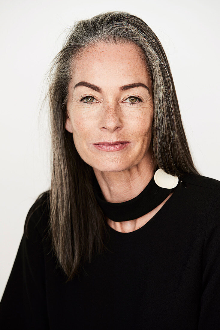 A woman with salt-and-pepper hair wearing a choker and a black blouse