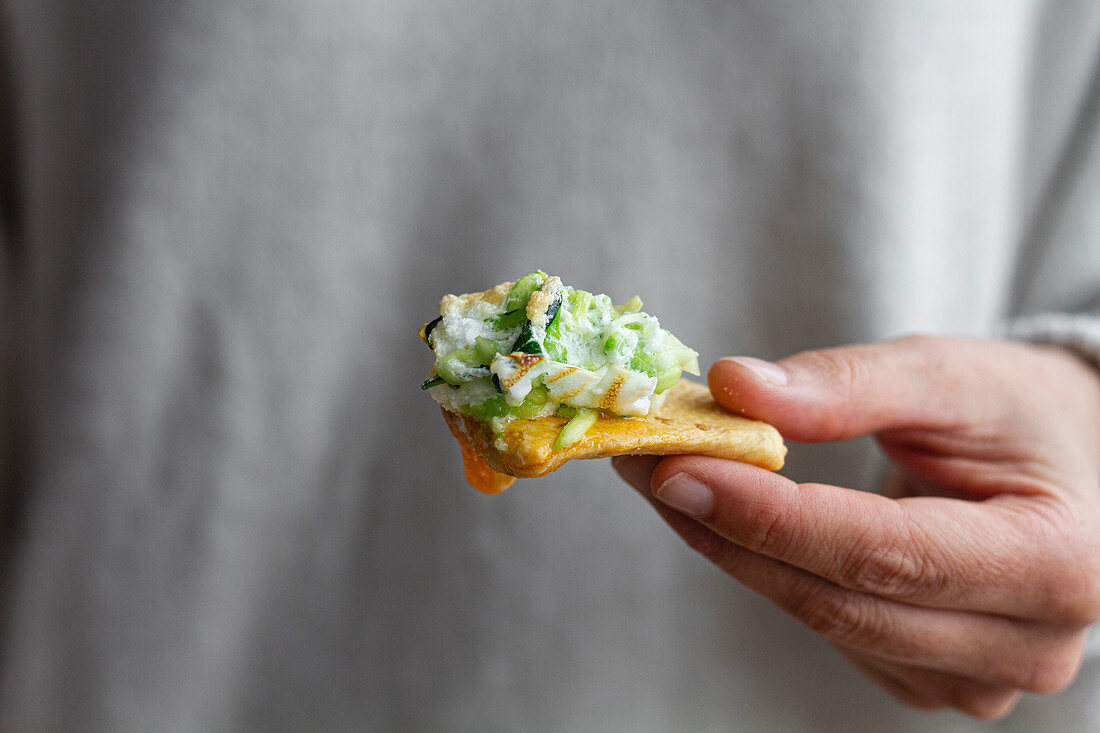 Hand hält Cracker mit Cloud Eggs und grünem Gemüse