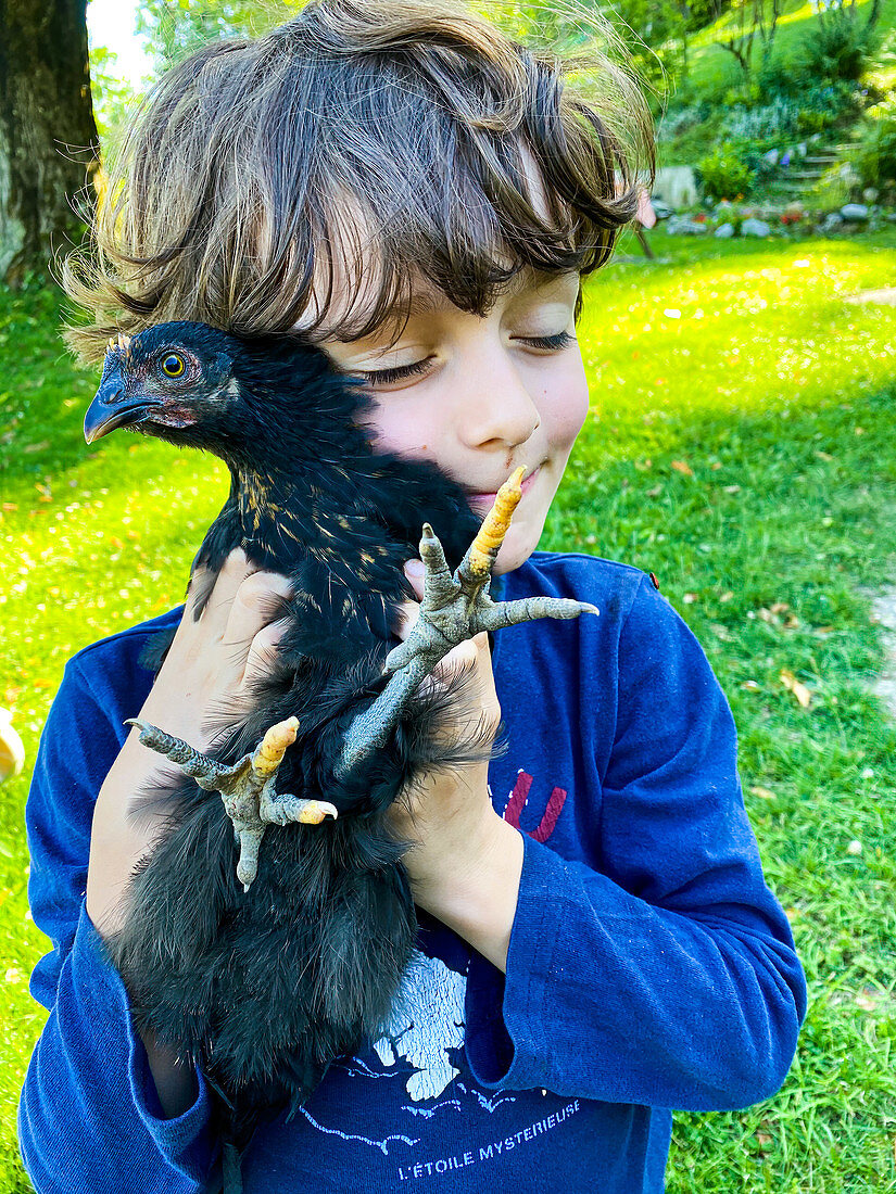 Child carrying a hen in his arms