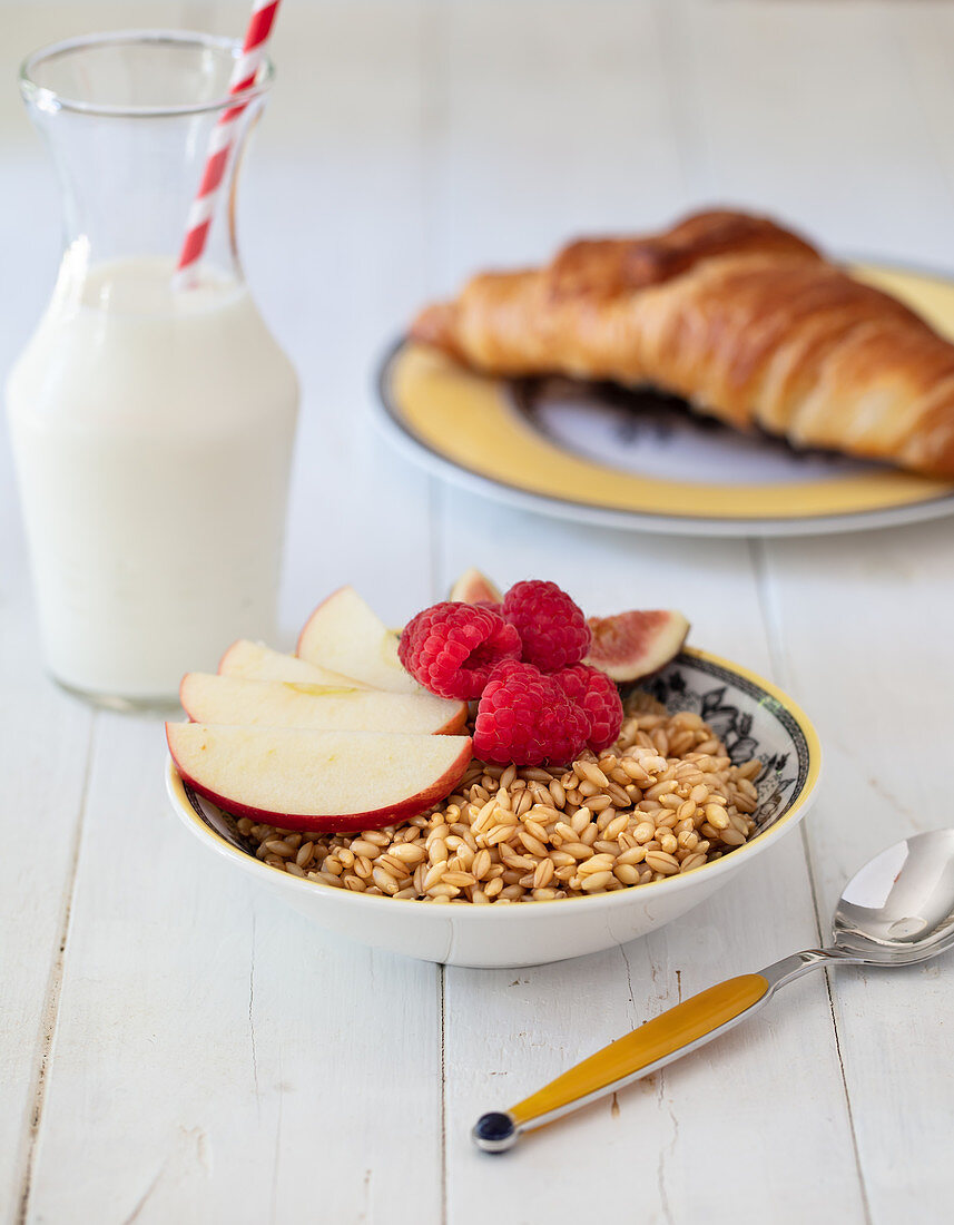 Breakfast with barley muesli, milk and croissant