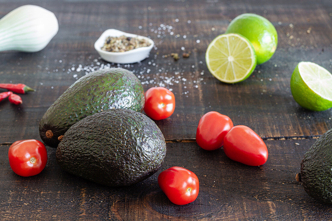 Zutaten für Guacamole (Avocado, Limetten, Tomaten, Frühlingszwiebel und Gewürze)