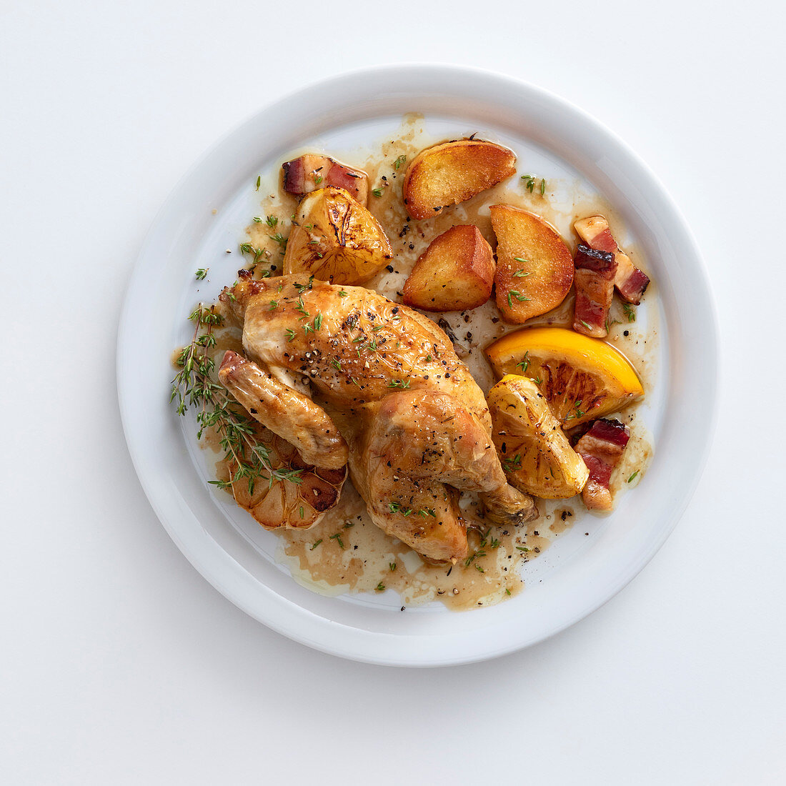 Lemon chicken with bacon, potatoes and thyme on a plate