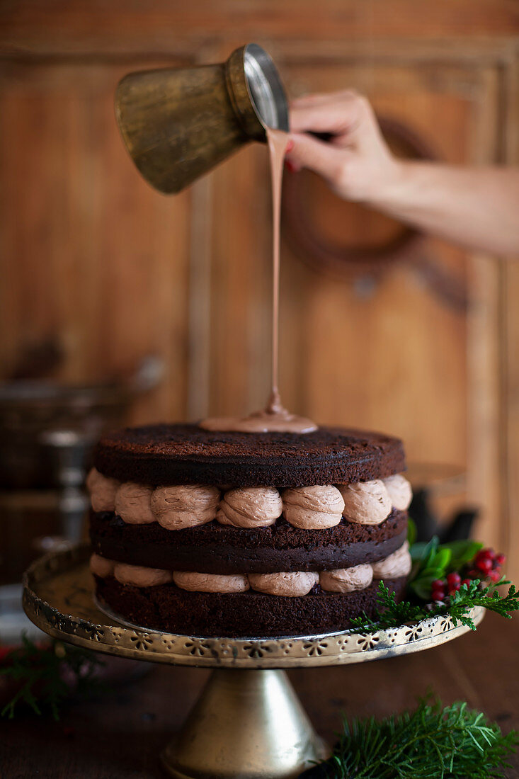 Ganache being poured over a chocolate cream cake