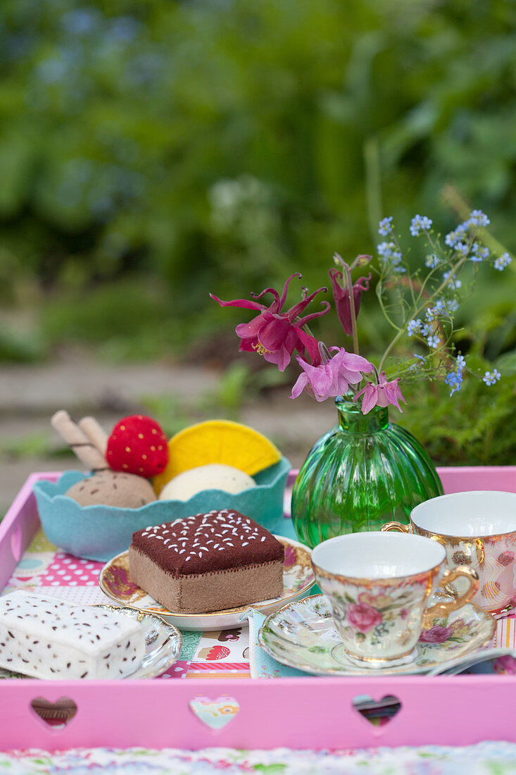Handmade felt cakes and ice-cream and china teacups on tray