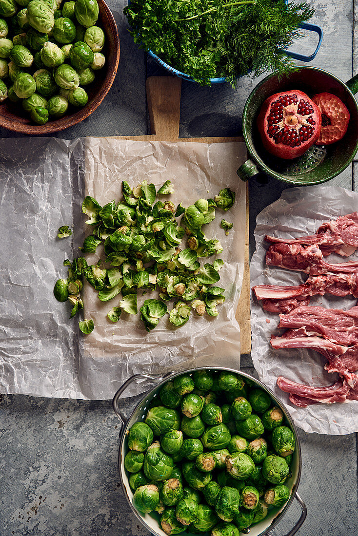 Cleaned Brussels sprouts in a colander, raw lamb chops and herbs
