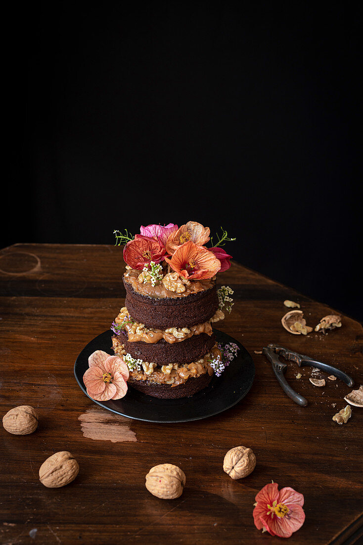 Chocolate naked cake with cream, walnuts and edible flowers