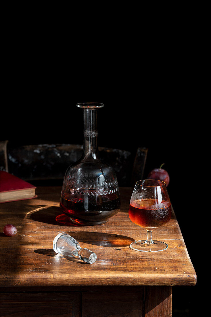Glass of cognac with ice cubes and decanter
