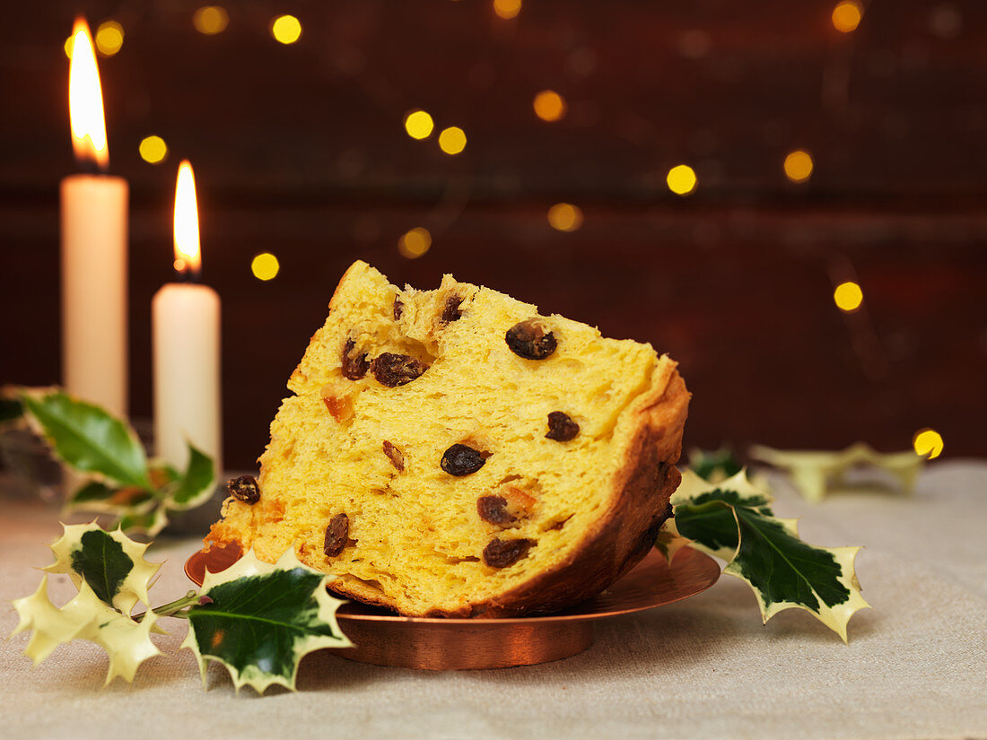 A piece of panettone with holly sprigs on a plate