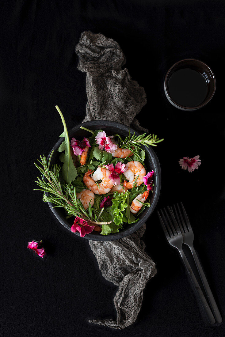 Salad with shrimps and green herbs garnished with eatible flowers