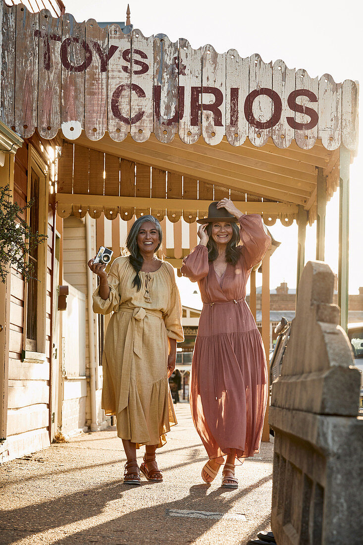 Two grey-haired women wearing dresses with a camera